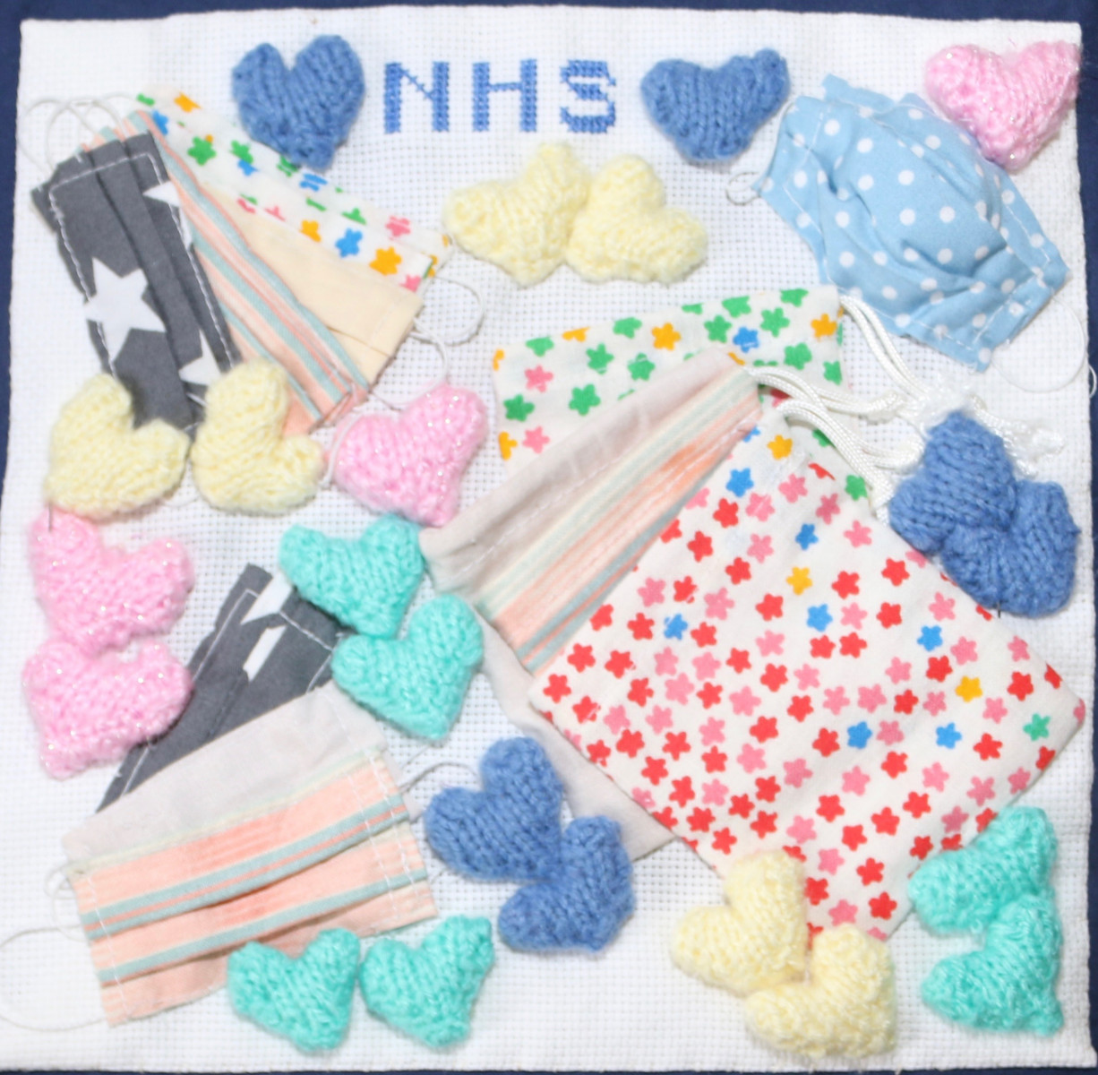 Collage of knitted hearts and material facemasks. NHS embroidered at the top