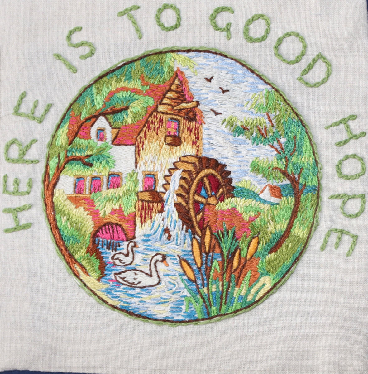 Embroidered picture of a water mill and swans. Words Here is to Good Hope embroidered above