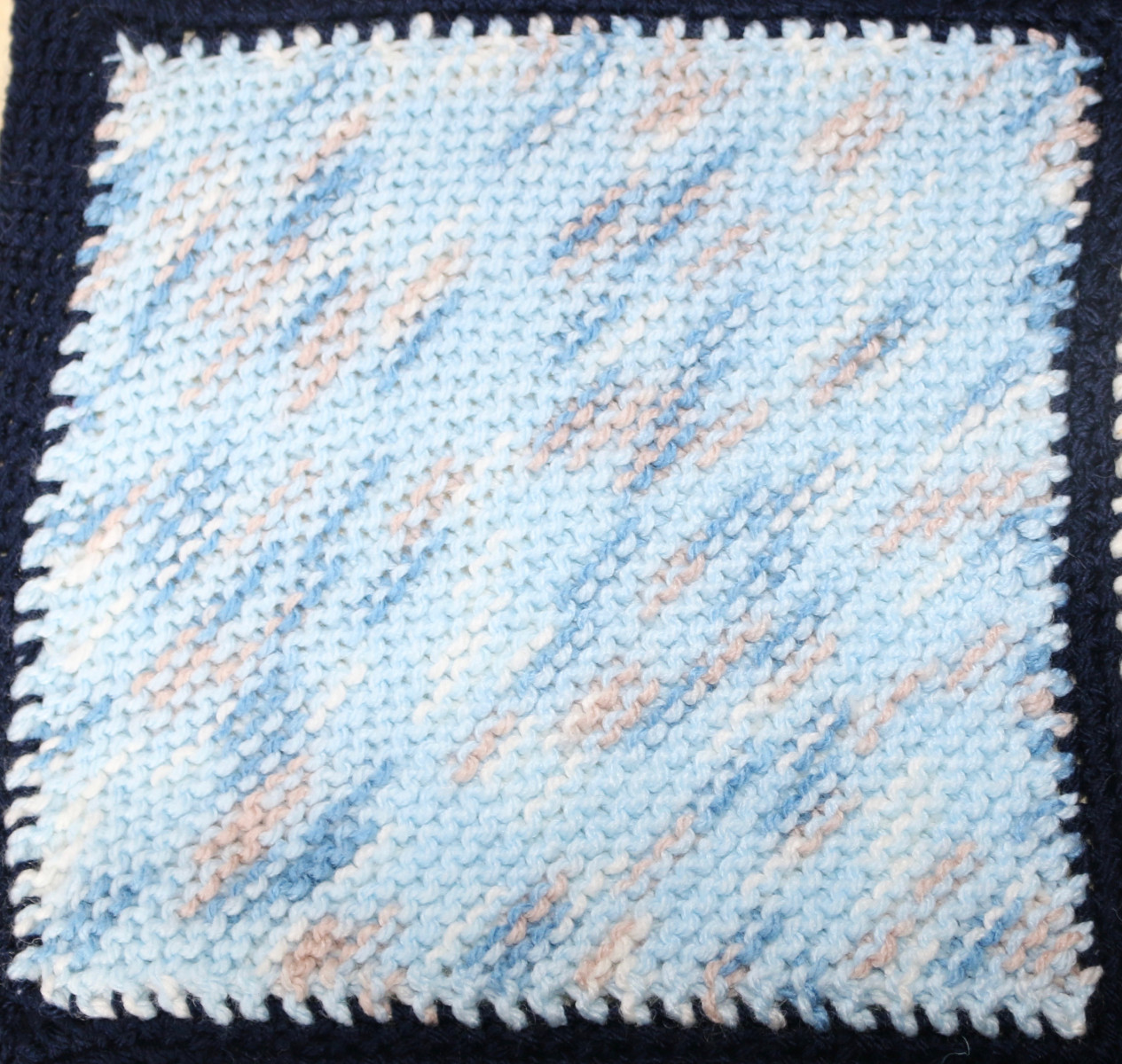 Knitted square in blue, pink and white