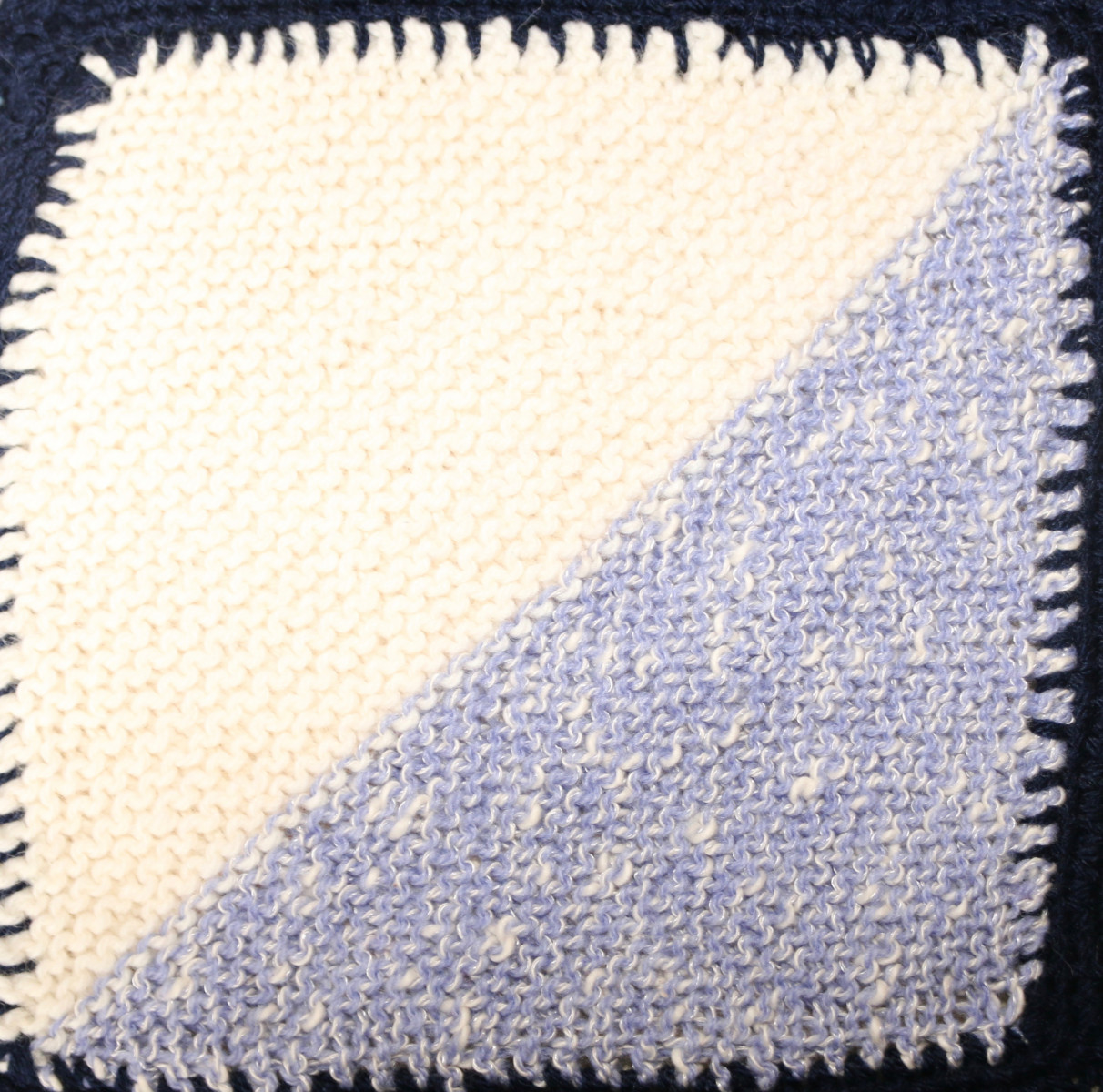 Knitted square: top left triangle white and bottom right triangle blue