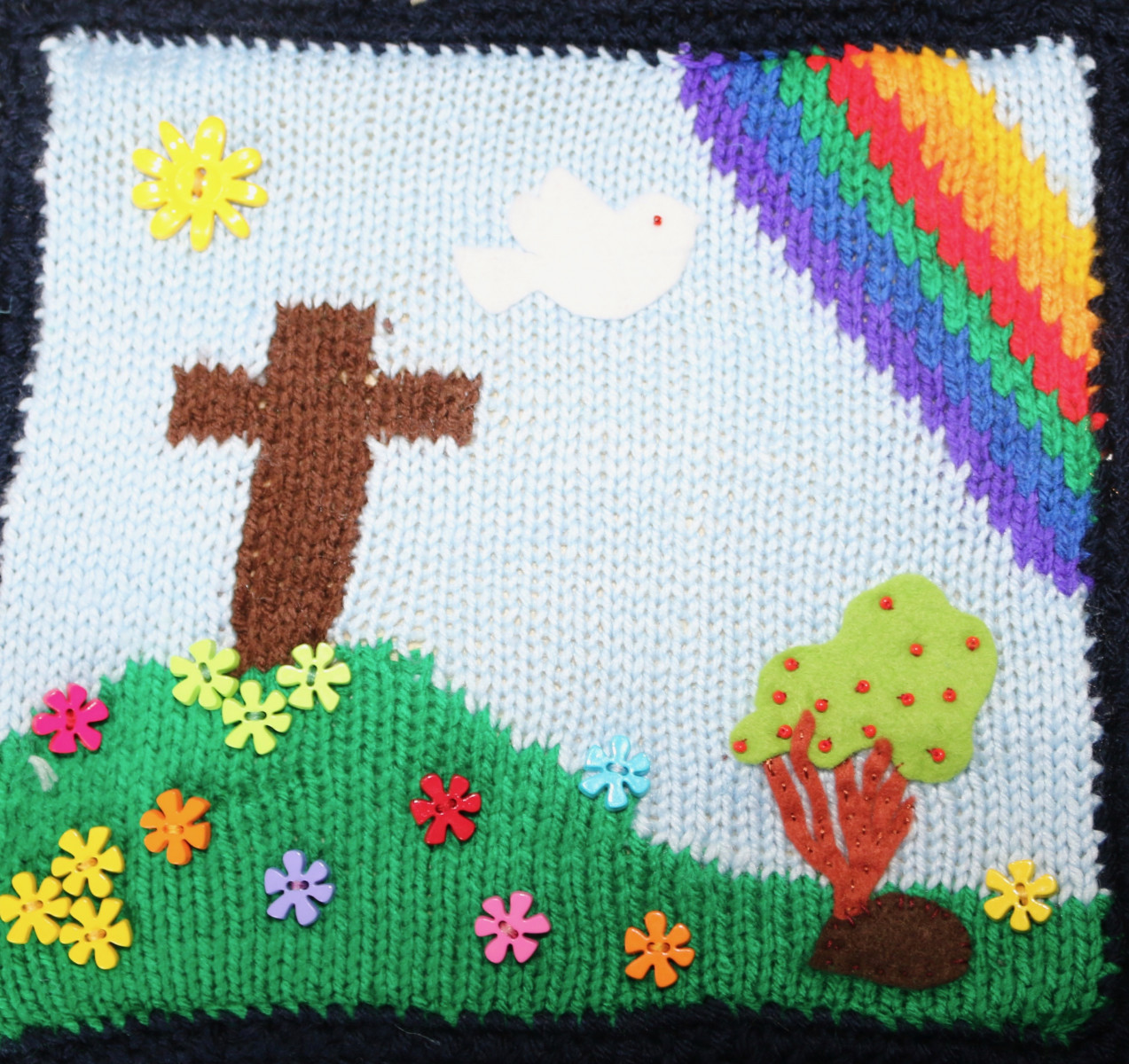 Knitted square: cross on a hillside, rainbow, a dove and a hedgehog