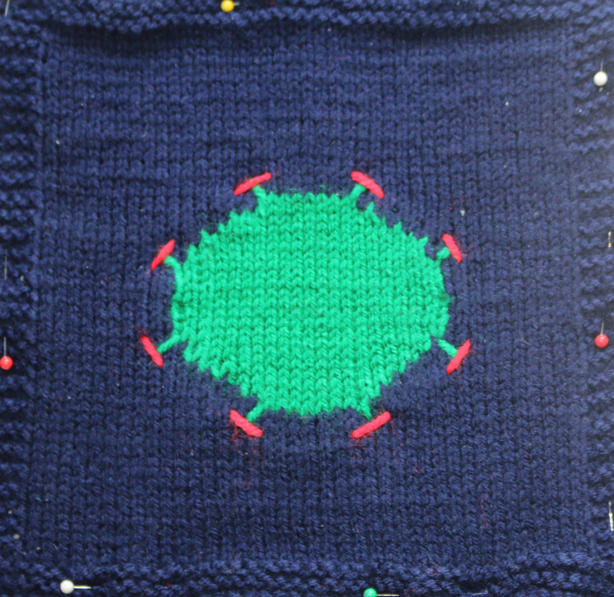 Knitted navy square with knitted image representing the Coronavirus