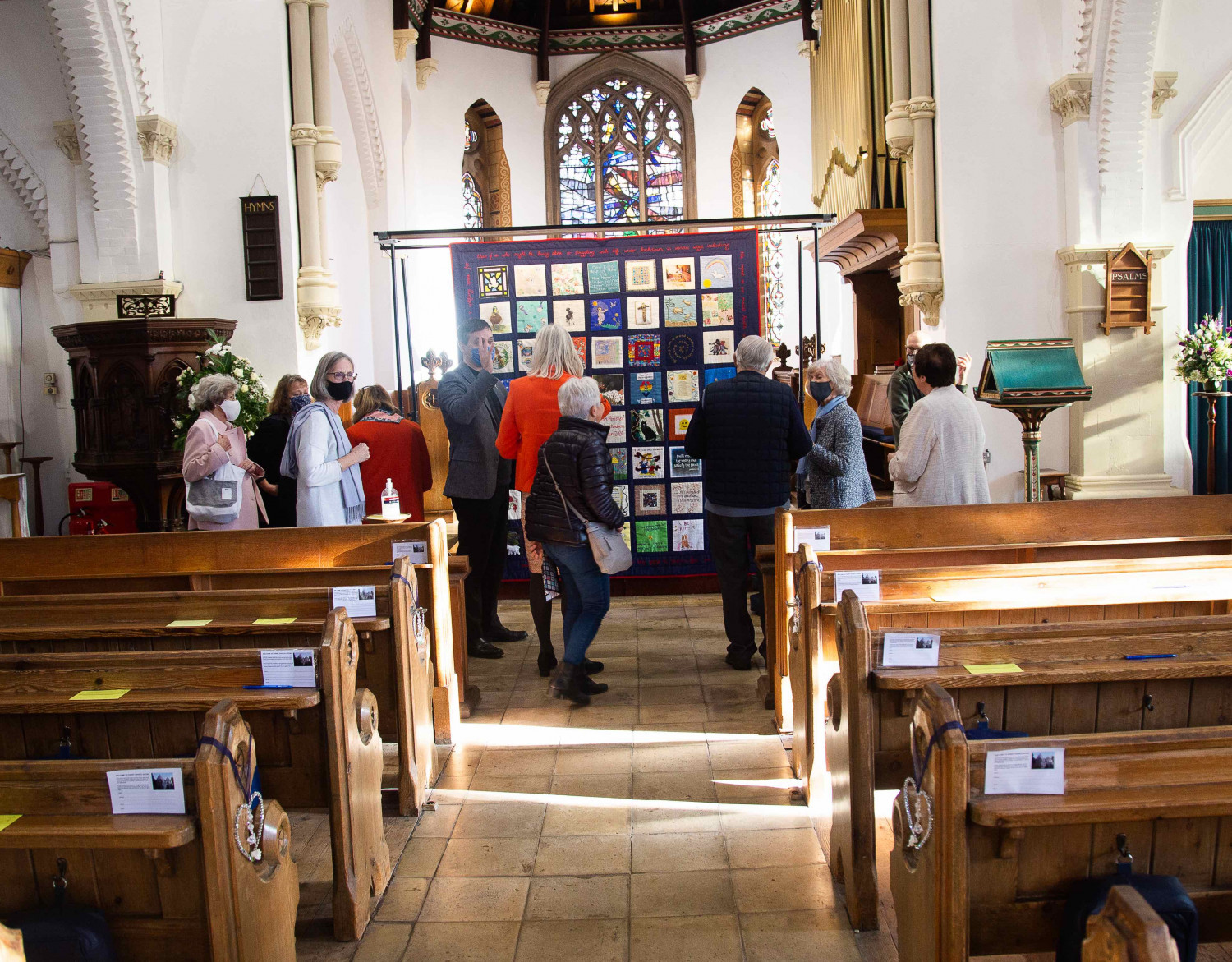 Photograph of people looking at a textile quilt in a church