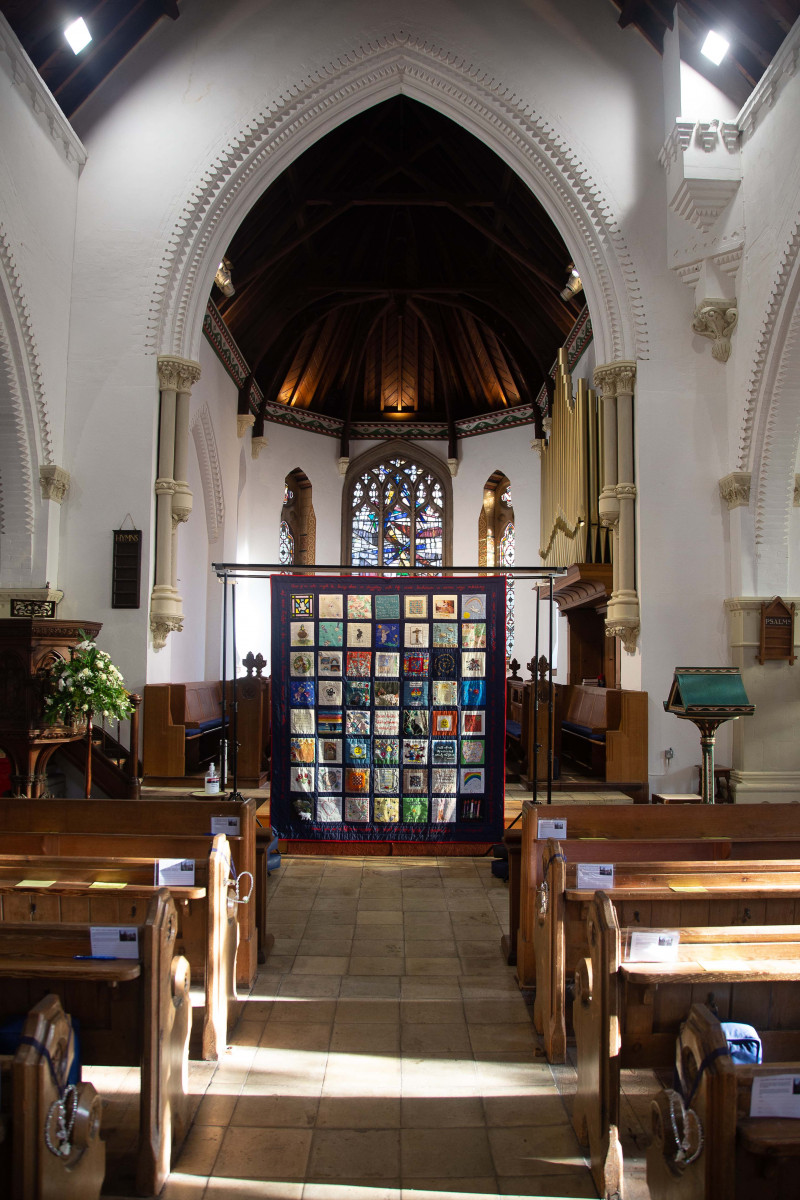 view from a distance of a textile quilt hanging in a Church nave